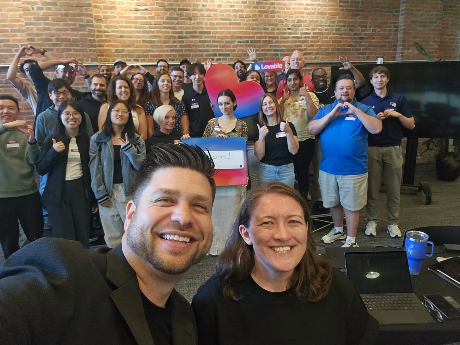 Group photo of workshop attendees holding a Lovable sign in a brick-walled loft