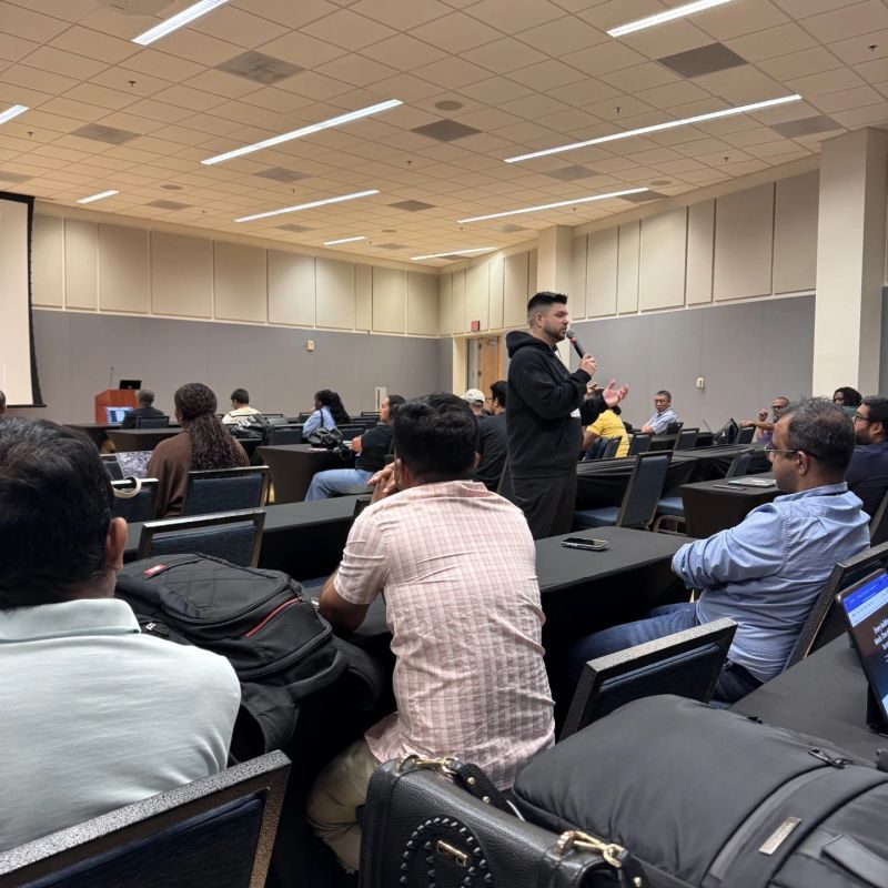 Presenter with a microphone addressing an audience seated at seminar tables